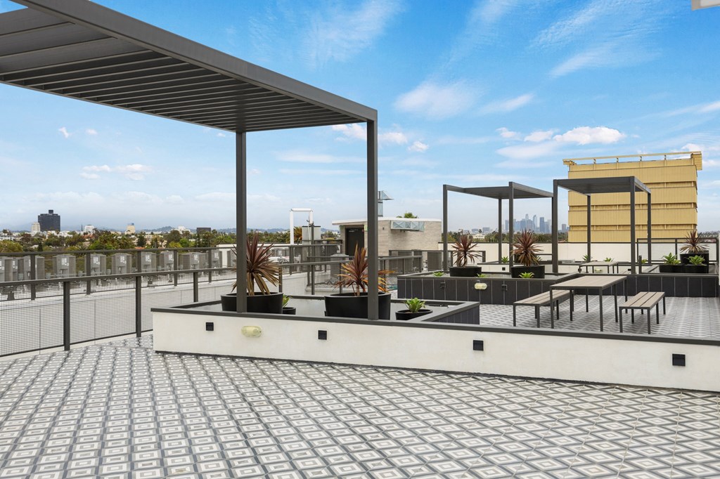 a roof deck with seating and a pergola at The Fairfax Flats Apartments, Los Angeles, CA, 90019