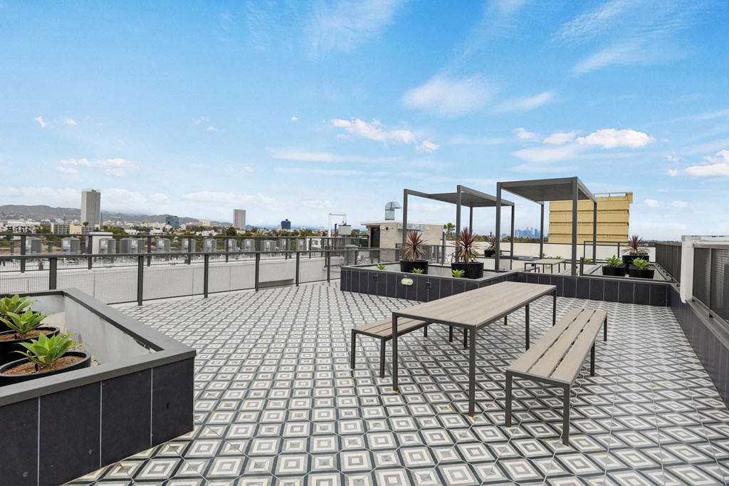 a roof deck with a picnic table and benches at The Fairfax Flats Apartments, Los Angeles, California