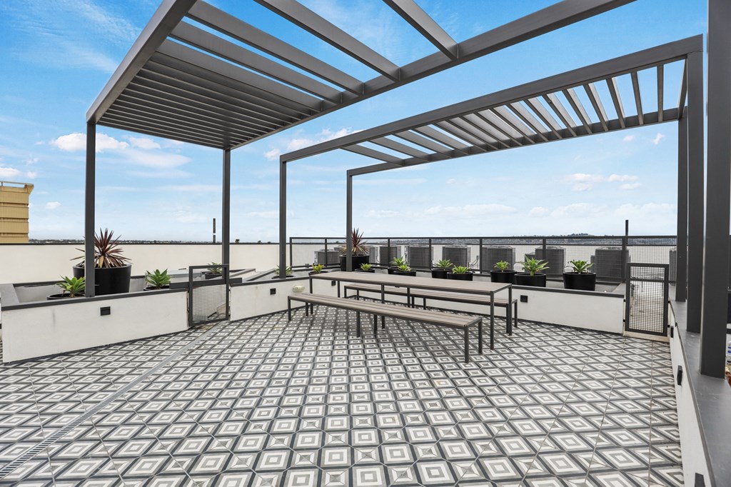 a view of the rooftop terrace of a building with a pergola and benches at The Fairfax Flats Apartments, Los Angeles, CA, 90019