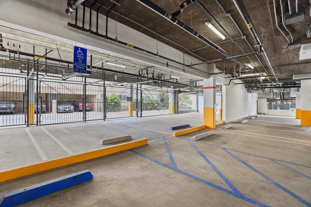 a large parking lot with a black fence and a red and white sign at The Fairfax Flats Apartments, California, 90019
