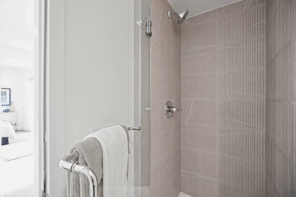 a bathroom with a shower and a towel rack at The Fairfax Flats Apartments, Los Angeles, CA