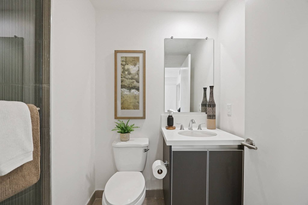 a small bathroom with a toilet sink and mirror at The Fairfax Flats Apartments, Los Angeles, CA