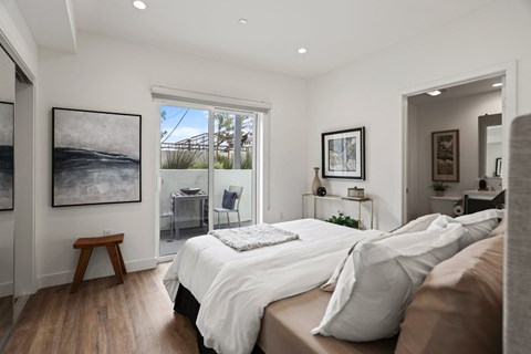 a bedroom with a bed and a door leading to a balcony at The Fairfax Flats Apartments, Los Angeles, CA, 90019