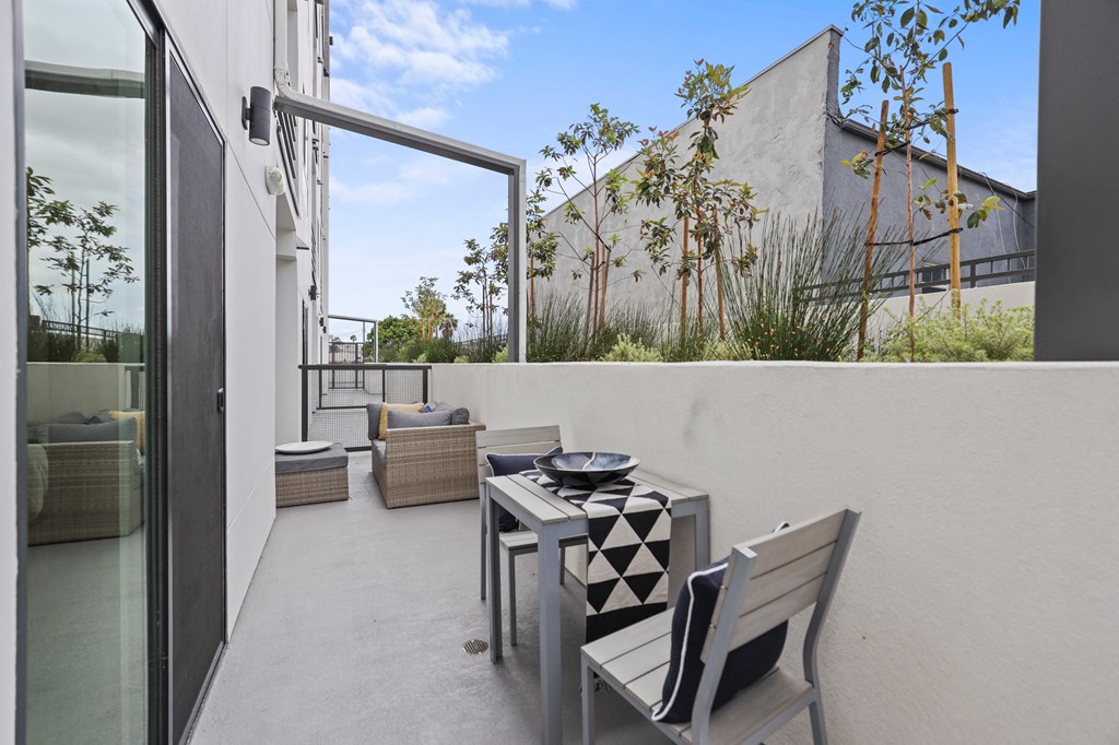 a small balcony with a table and chairs at The Fairfax Flats Apartments, Los Angeles, California