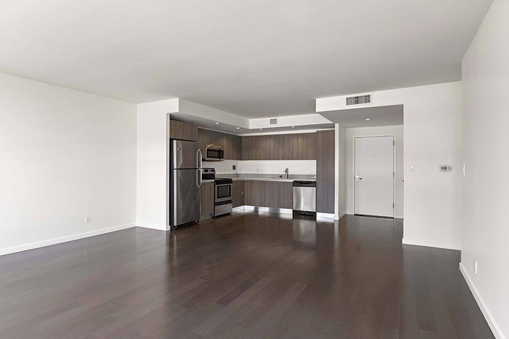 A kitchen with dark wood floors and white walls.