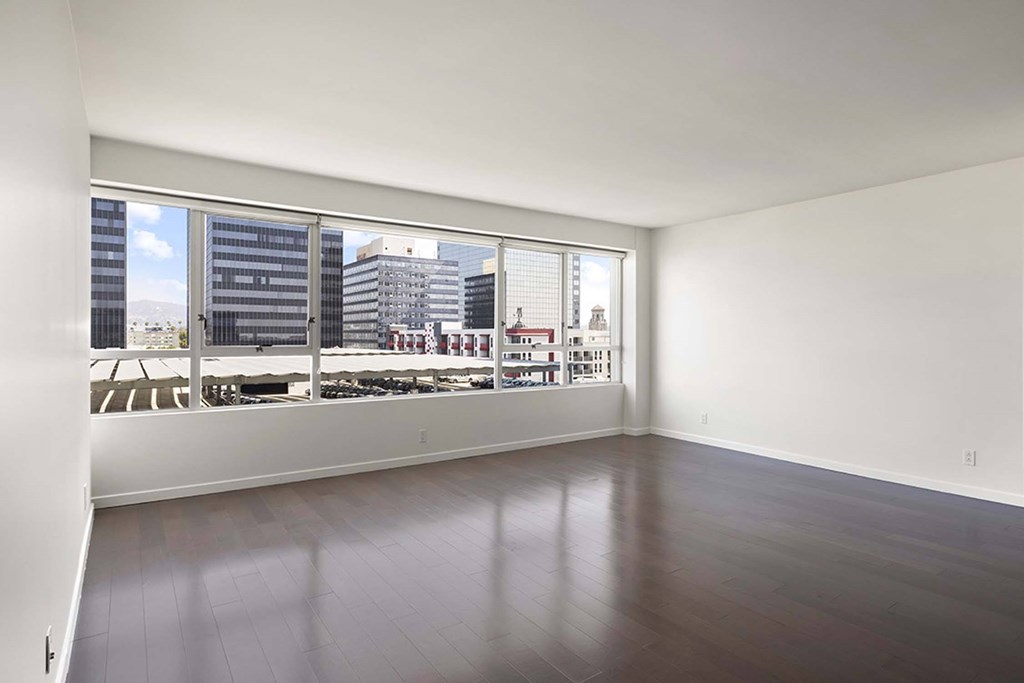 A large empty room with a view of the city outside the window.