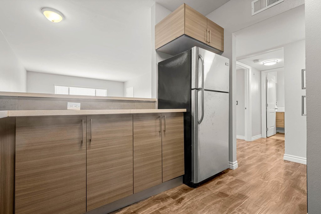A modern kitchen with a black refrigerator and wooden cabinets at Lafayette Apartments, California, 90019