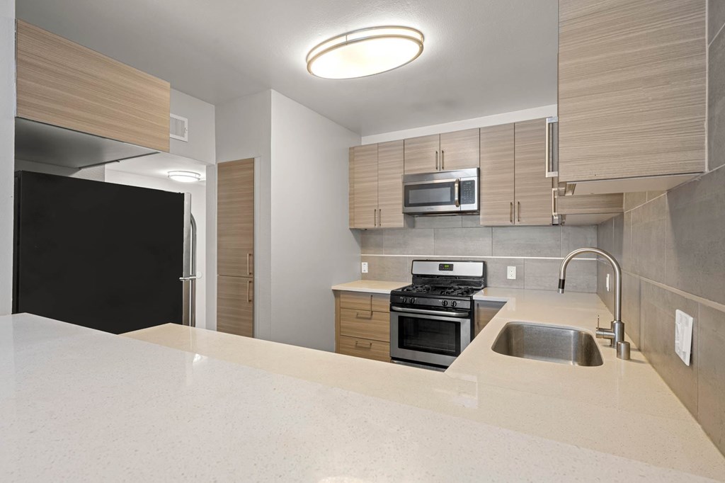 A modern kitchen with a black refrigerator and stove at Lafayette Apartments, Los Angeles, CA, 90019