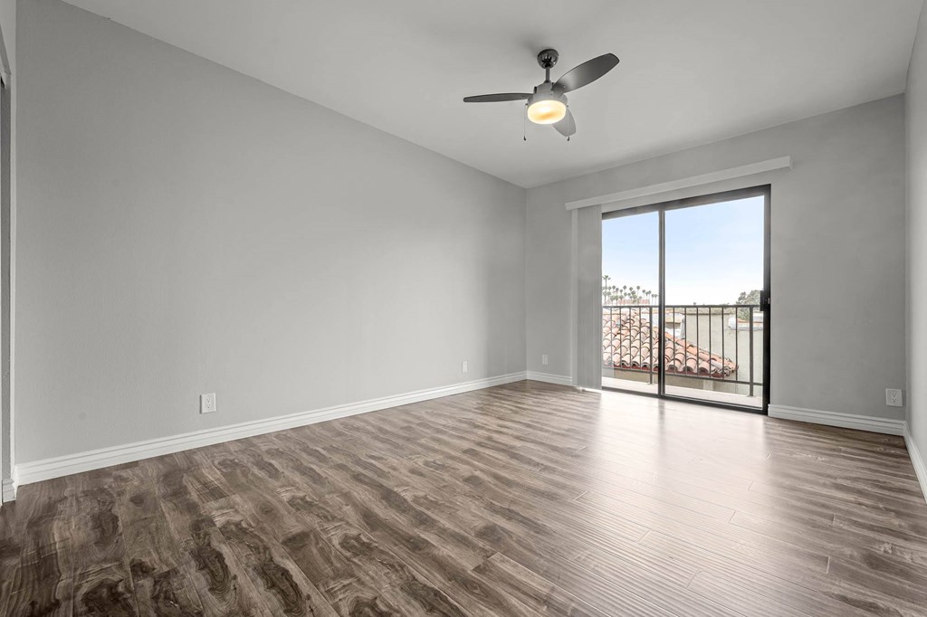 A room with a ceiling fan and sliding glass doors leading to a balcony at Lafayette Apartments, Los Angeles
