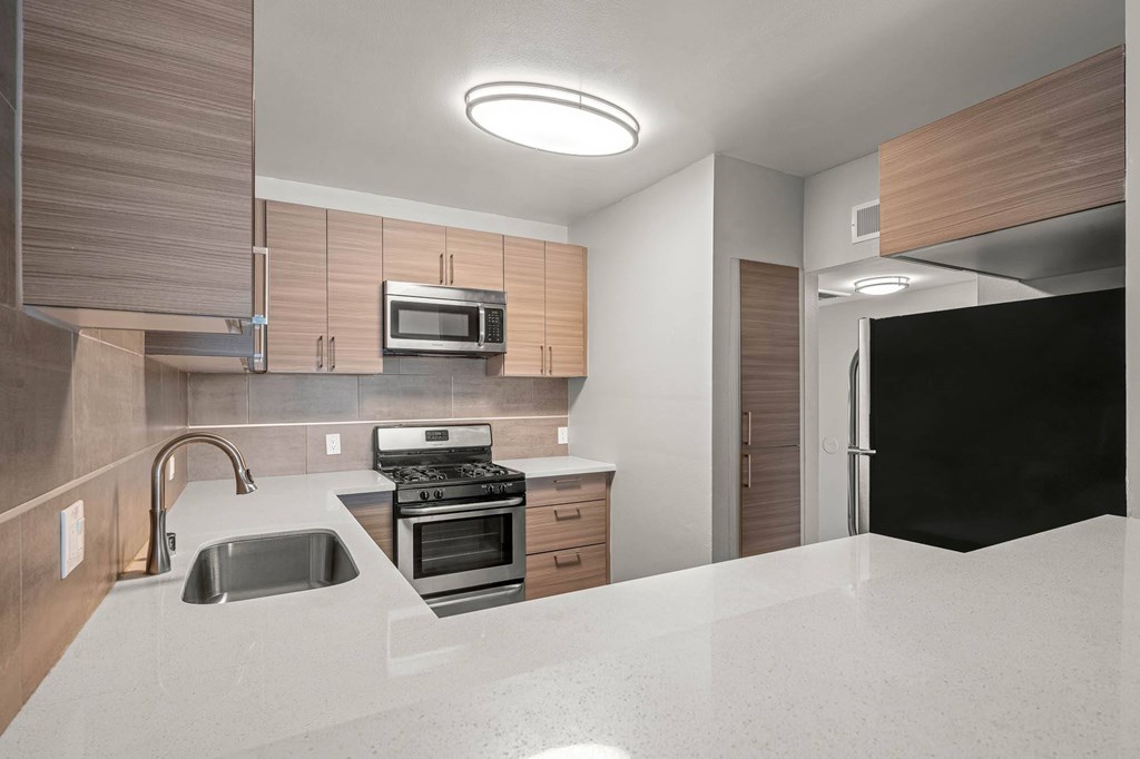 A modern kitchen with a sink, stove, and microwave at Lafayette Apartments, Los Angeles, CA