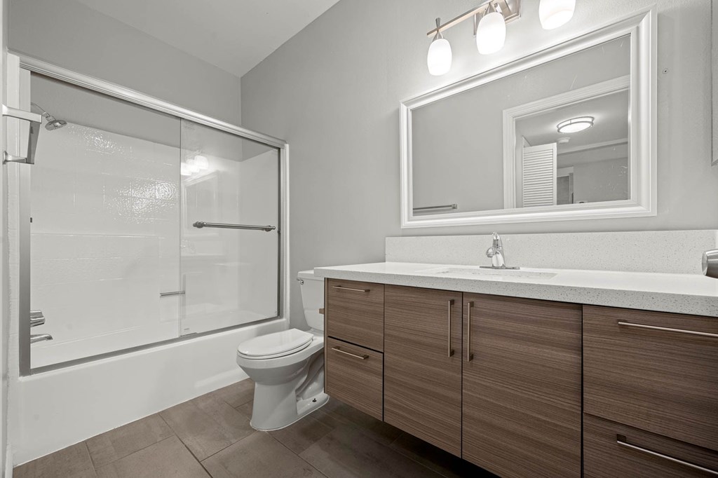 A bathroom with a toilet, sink, and mirror at Lafayette Apartments, California
