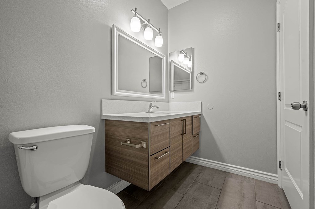 A bathroom with a toilet, sink, and mirror at Lafayette Apartments, Los Angeles 90019