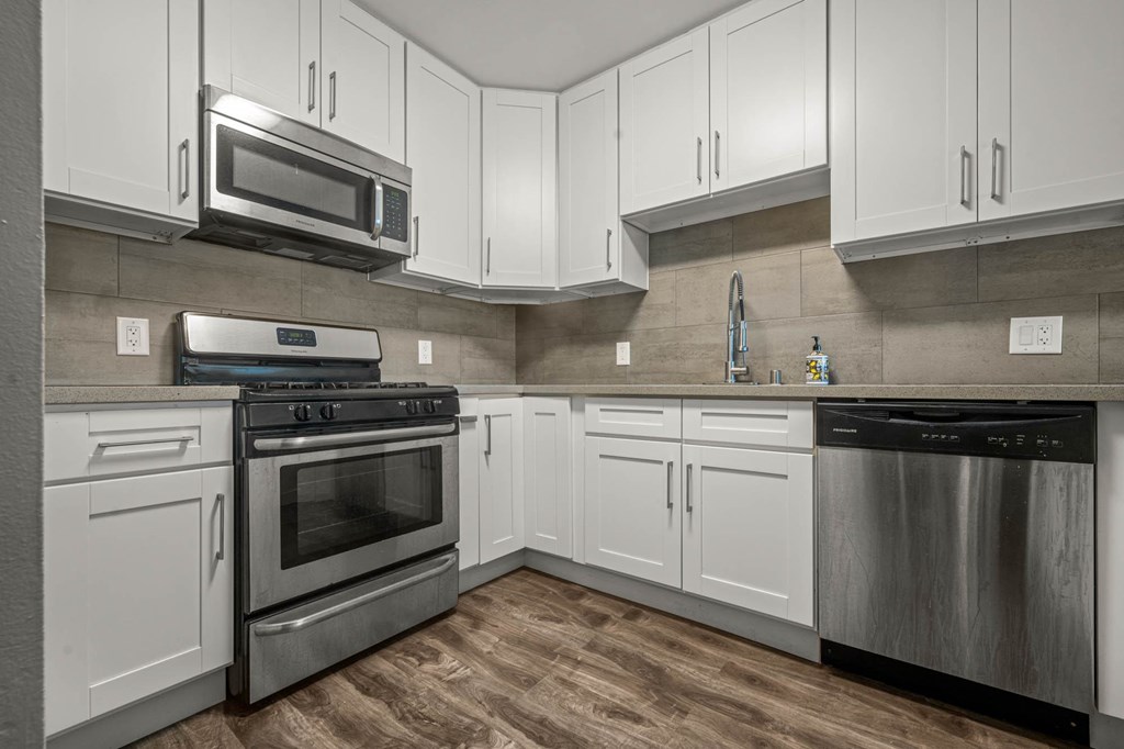 A modern kitchen with white cabinets and stainless steel appliances at Lafayette Apartments, Los Angeles