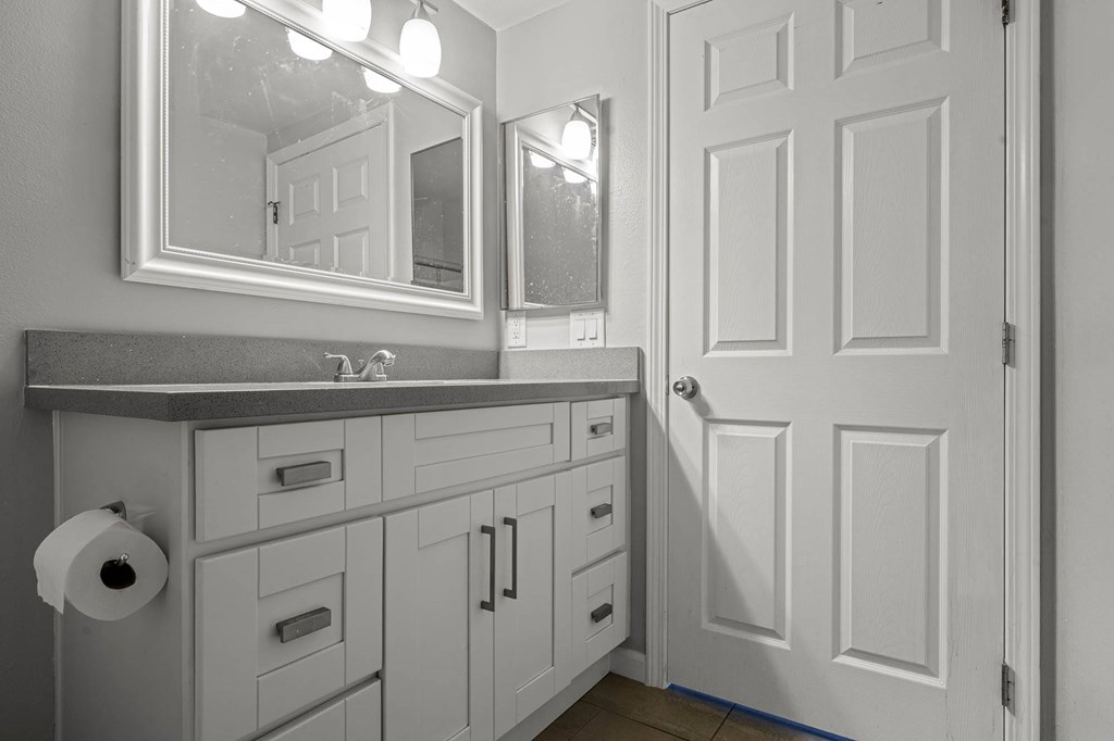 A bathroom with a white door and a mirror above it at Lafayette Apartments, Los Angeles, CA