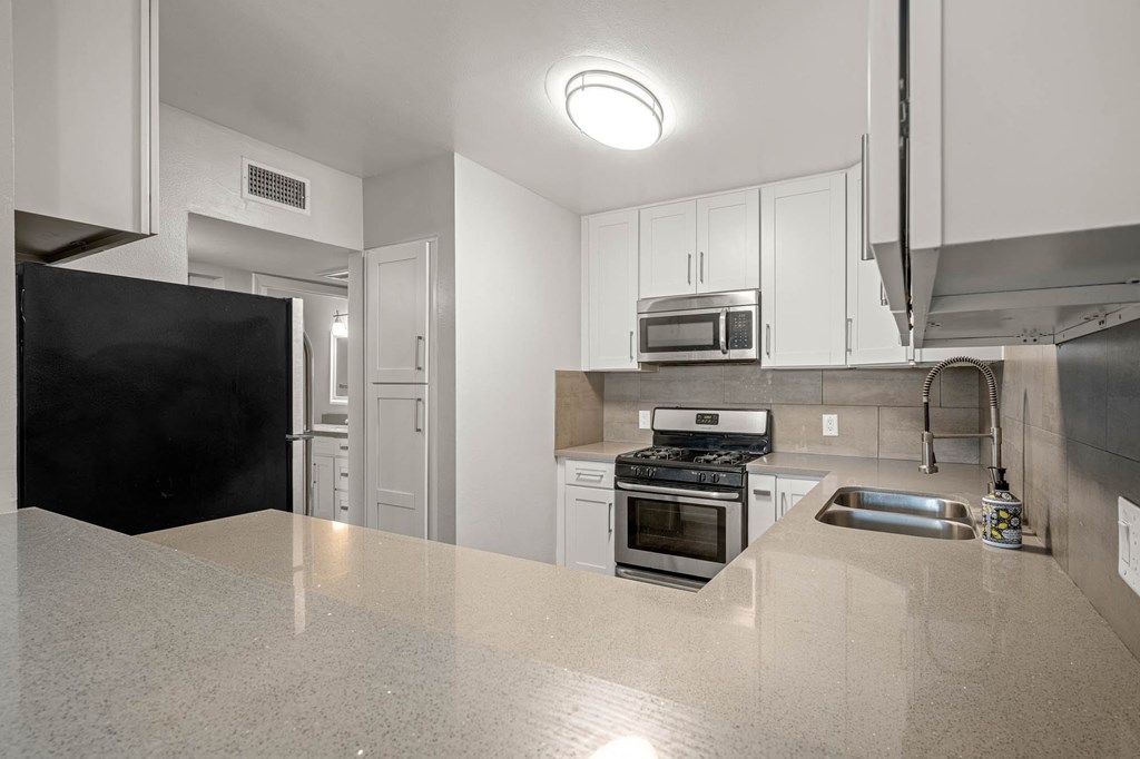 A kitchen with white cabinets and stainless steel appliances at Lafayette Apartments, Los Angeles, California