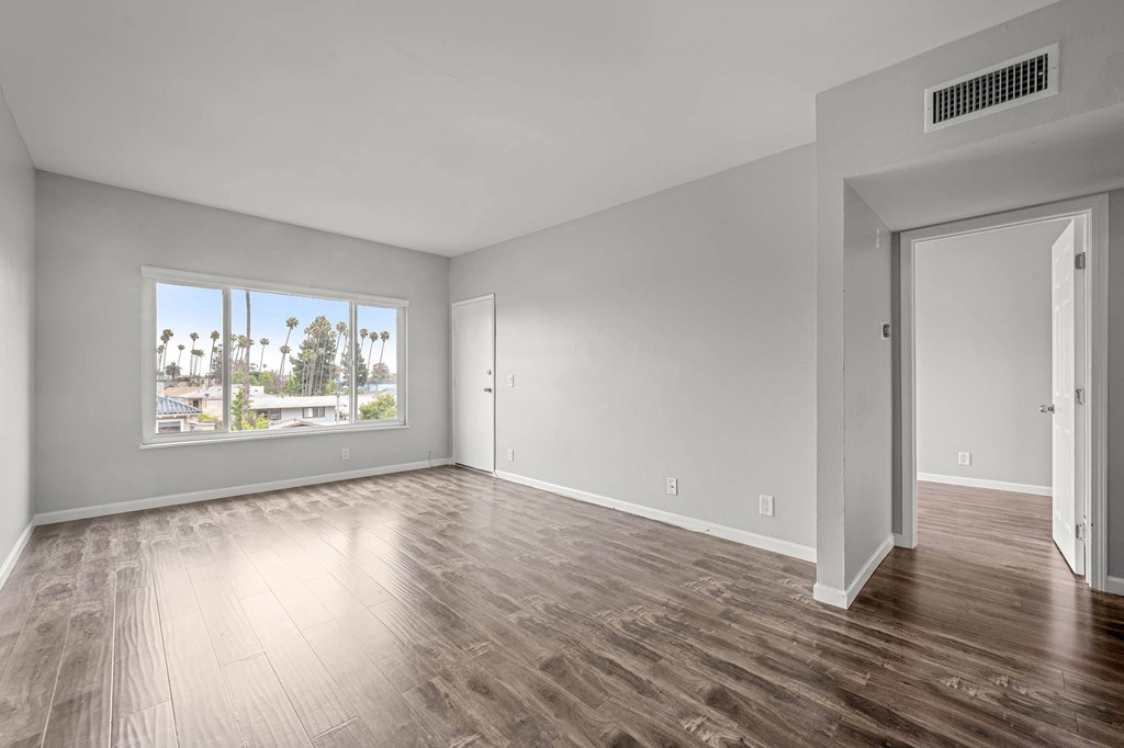 A room with wooden flooring and a large window overlooking a cityscape at Lafayette Apartments, Los Angeles, CA