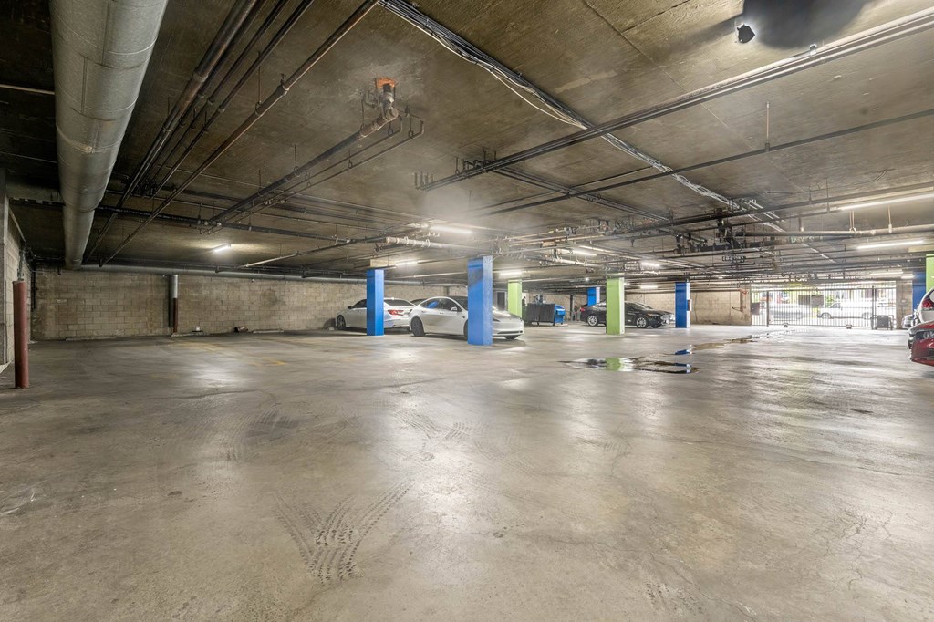 A parking garage with a concrete floor and multiple cars parked at Lafayette Apartments, California, 90019