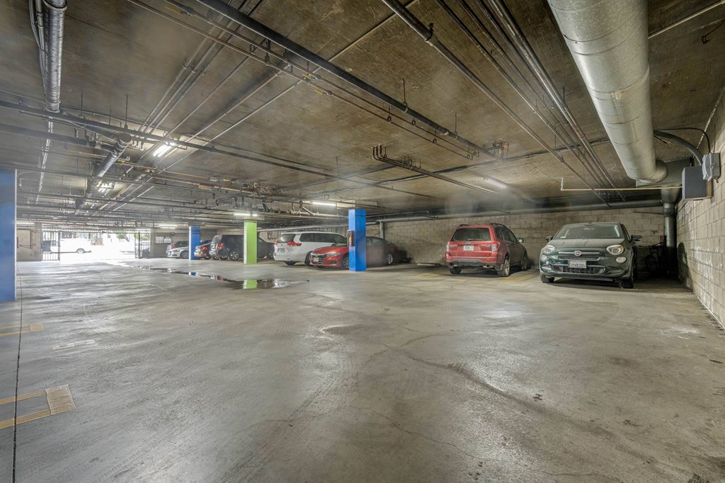 A parking garage with a few cars and a blue wall at Lafayette Apartments, Los Angeles, California
