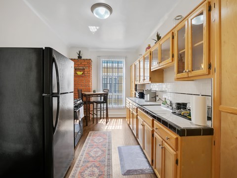 A kitchen with wooden cabinets and a black fridge.