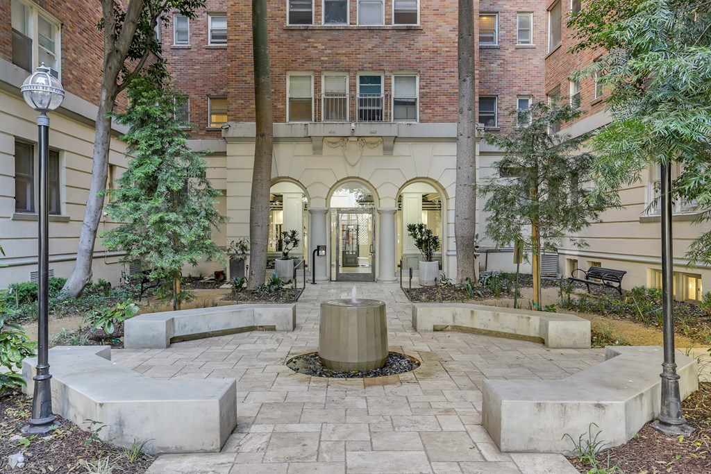 A courtyard with a fountain surrounded by trees and benches.
