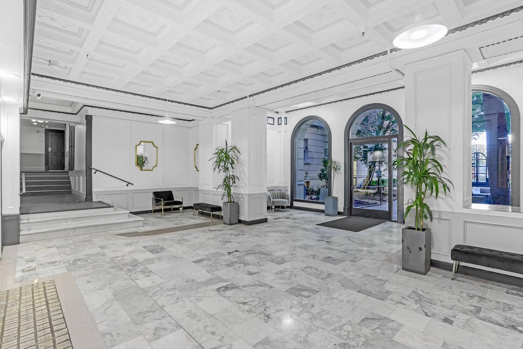 A white hallway with marble floors and a staircase.