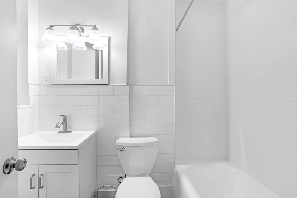 A white bathroom with a toilet, sink, and mirror.