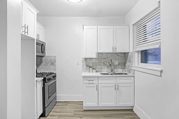 A kitchen with white cabinets and a marble backsplash.