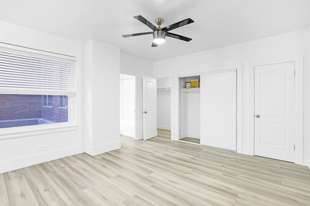 A room with a ceiling fan and wooden flooring.