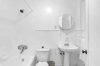 A white bathroom with a toilet, sink, and mirror.