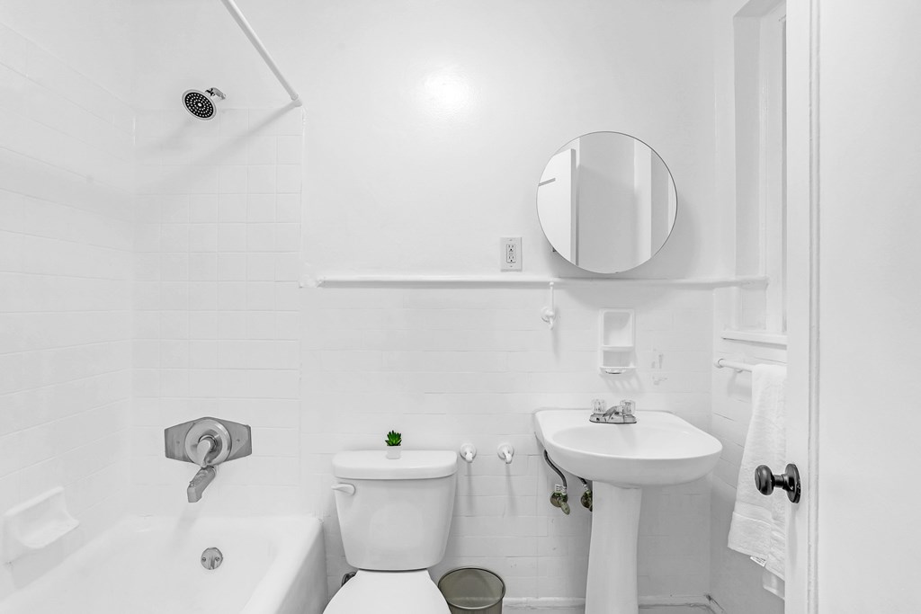 A white bathroom with a toilet, sink, and mirror.