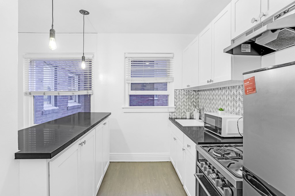 A kitchen with white cabinets and a black countertop.