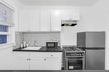 A kitchen with white cabinets and a black stove top.