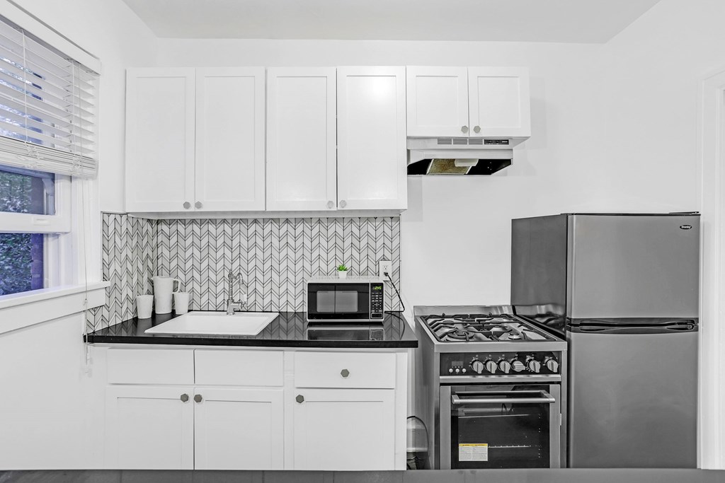 A kitchen with white cabinets and a black stove top.