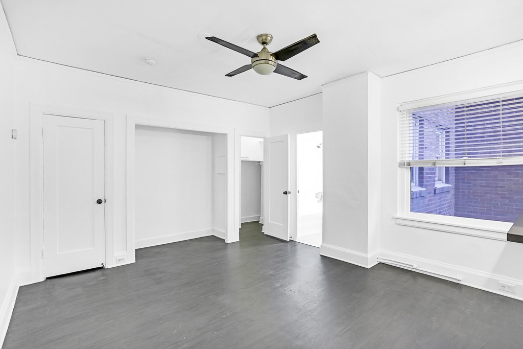A room with a ceiling fan and a window with blinds.