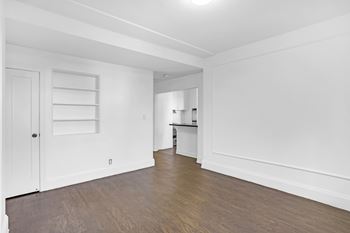 A white room with a wooden floor and a door on the left.
