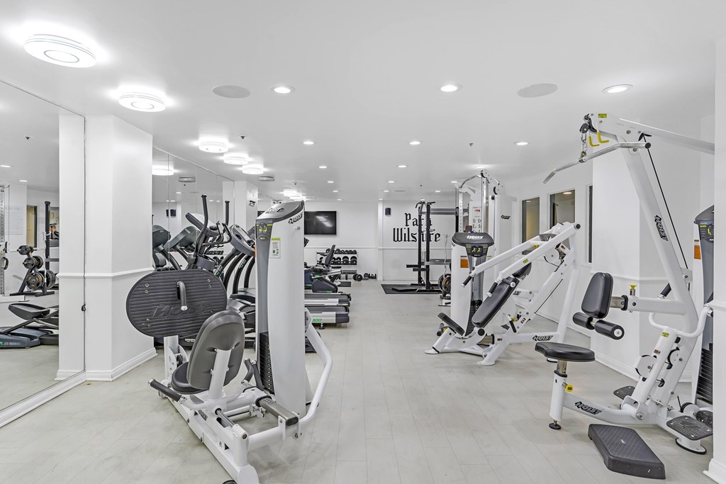 A gym with a variety of equipment including treadmills, weights, and exercise machines.