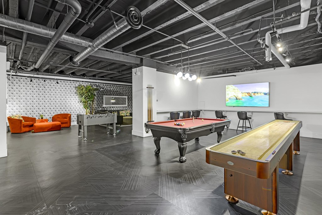 A pool table is in the middle of a room with a TV on the wall.