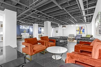 A room with orange chairs and a black table.