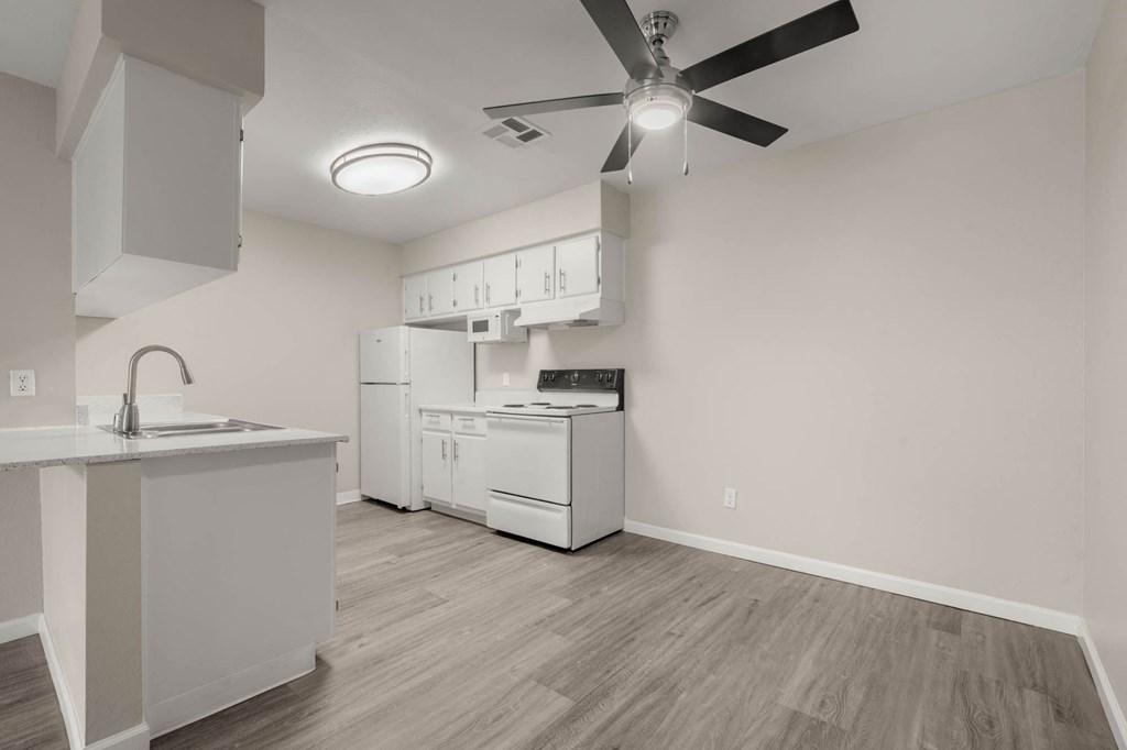 a kitchen with white appliances and a ceiling fan