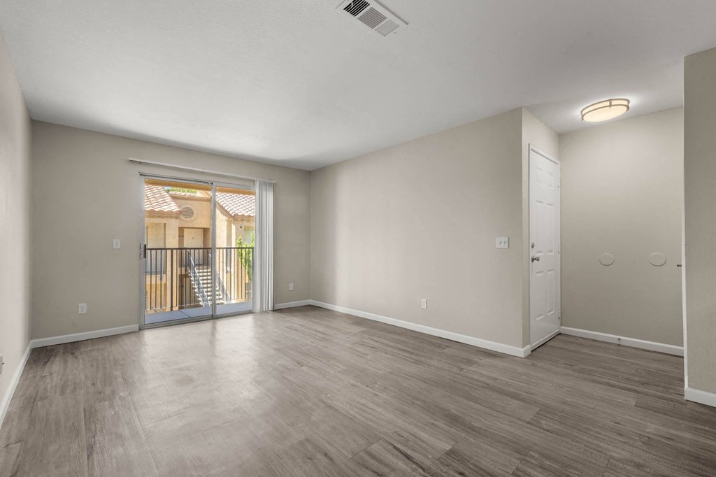 an empty living room with a door to a balcony