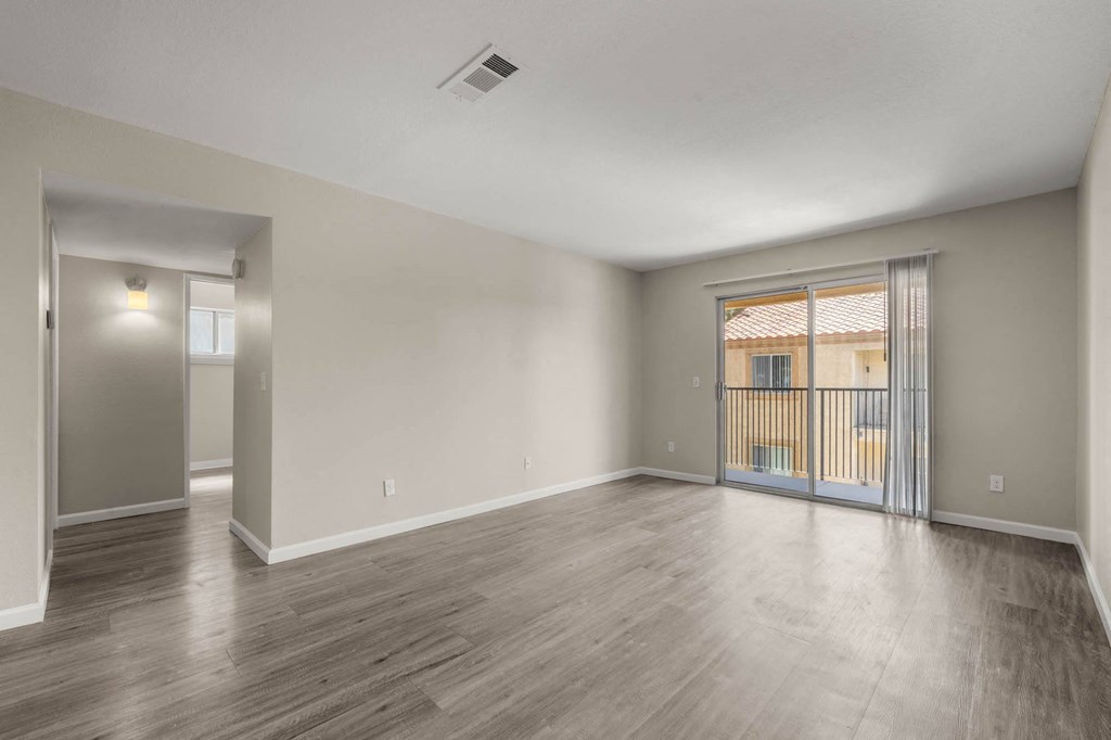 the living room of a new home with a large window and wood flooring