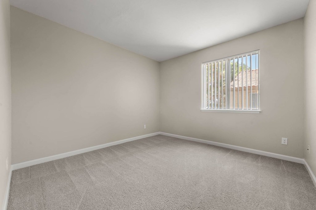 an empty living room with a window and carpet