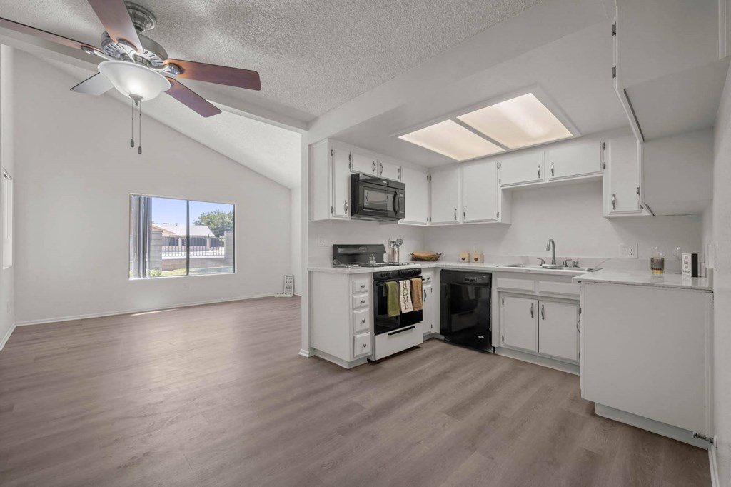 a white kitchen with a ceiling fan and a window