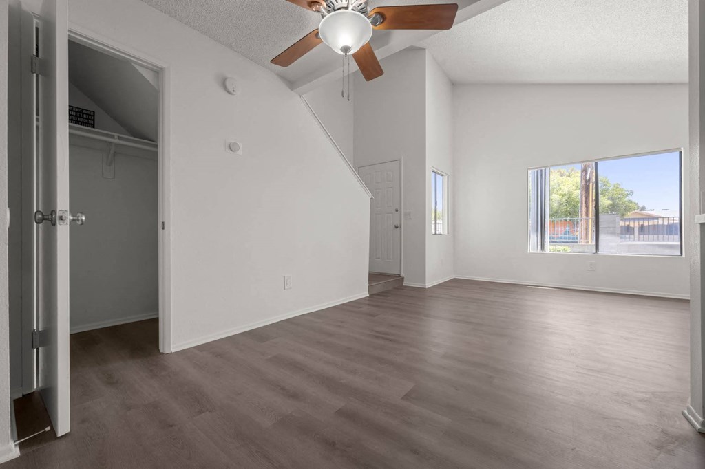 an empty living room with a ceiling fan and a window