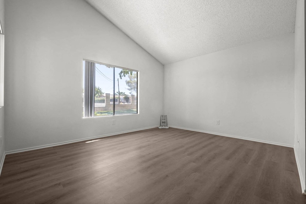 an empty living room with wood floors and a window