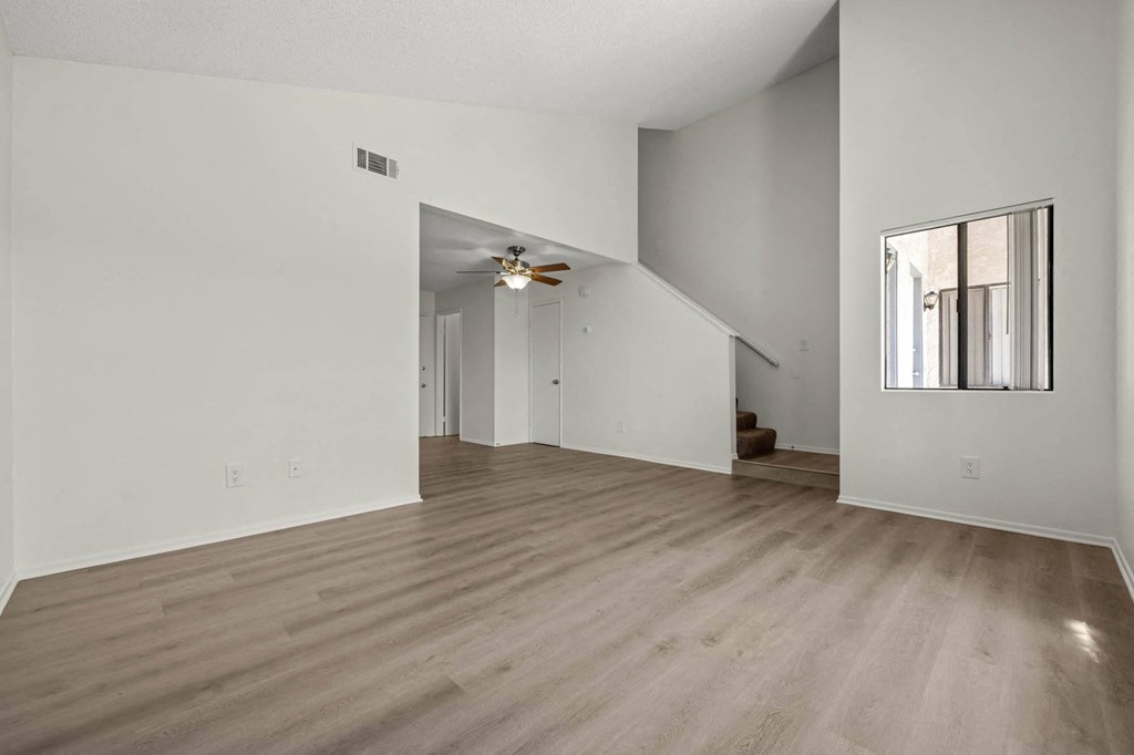 the living room and dining room of a house with white walls and wood floors