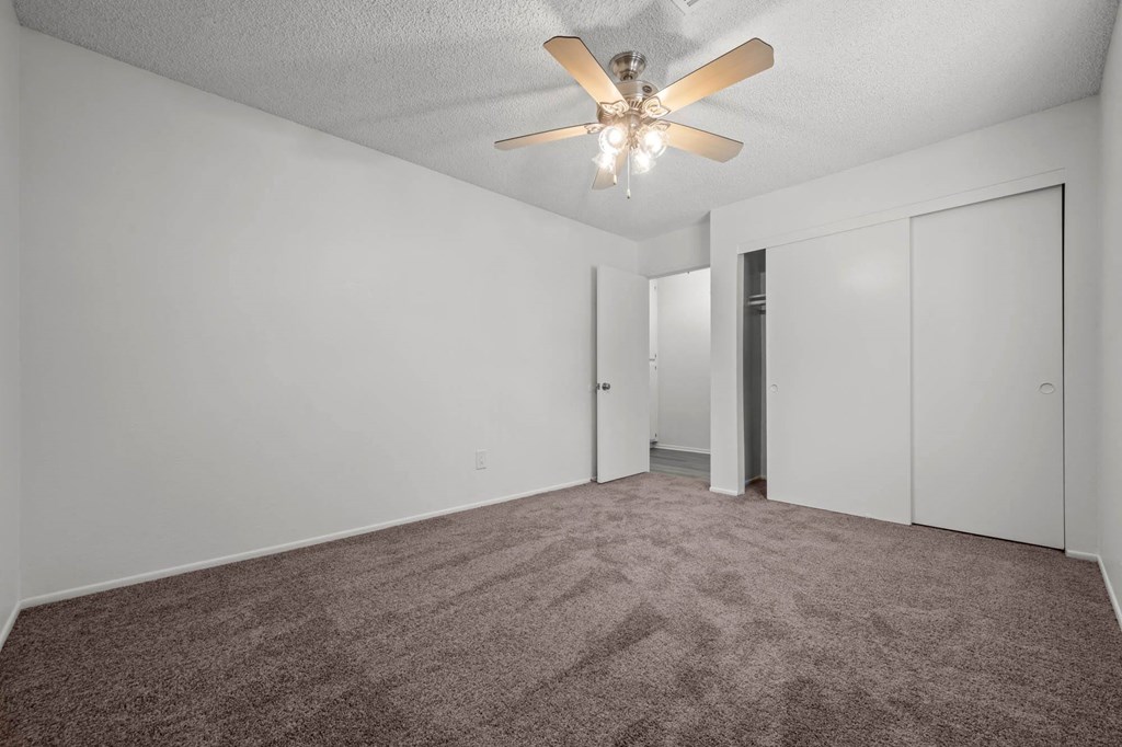 an empty living room with white walls and a ceiling fan