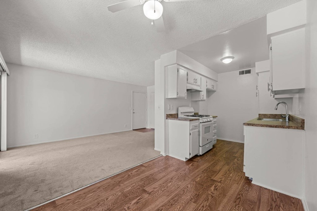 an empty living room and kitchen with a hard wood floor
