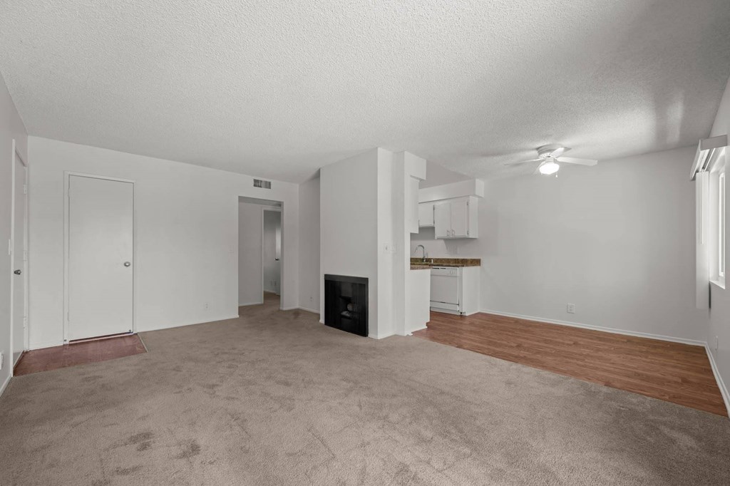 an empty living room with a fireplace and a kitchen