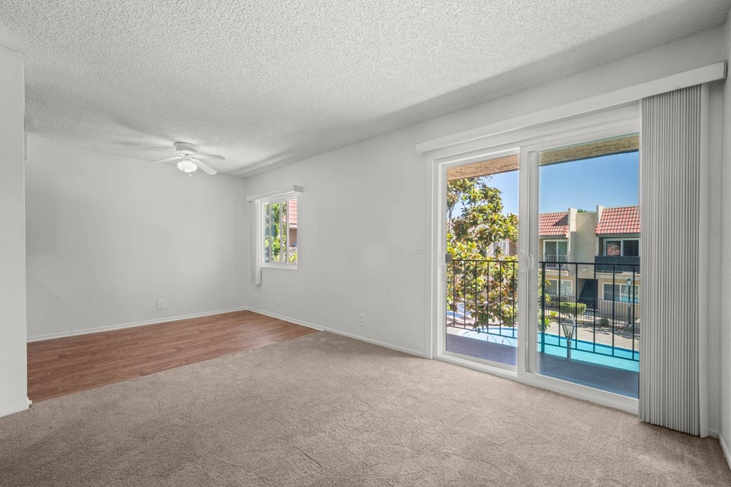 an empty living room with a sliding glass door to a pool